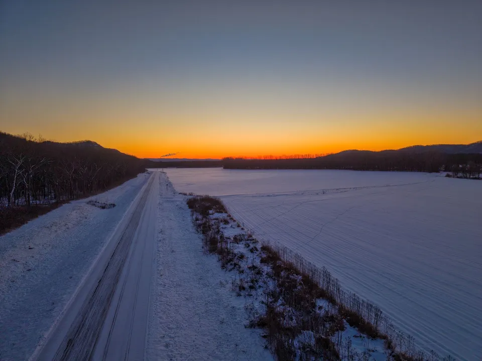 Aerial view of snowy Kellogg, Minnesota at sunset, with vivid colors and a serene winter landscape.