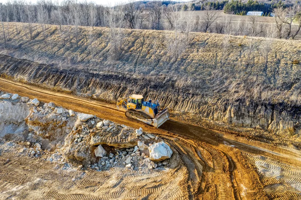 A bulldozer operating on a dirt road, preparing the landscape for construction in a rural setting.