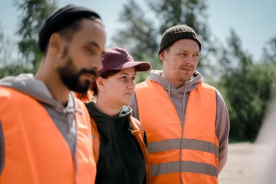 Group of workers wearing reflective vests outdoors, exemplifying teamwork and safety.