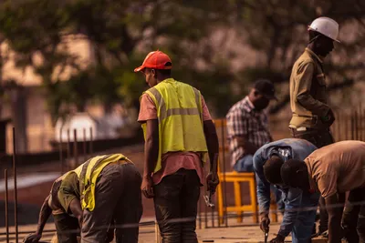Group of male construction workers on site wearing safety gear during daytime.