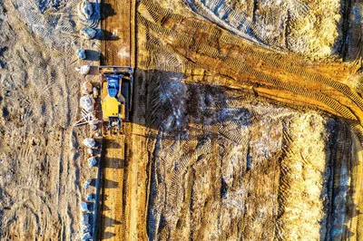 Top-down view of a bulldozer moving sand and rocks at a construction site in Rochester, MN.