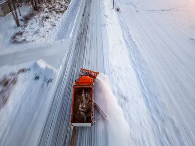 An orange snowplow clears a snow-covered road in Kellogg, Minnesota during winter.