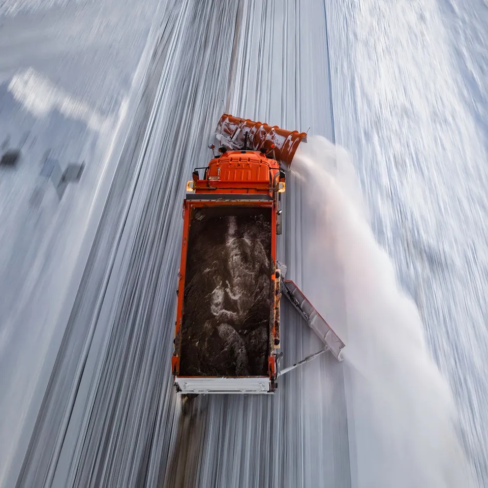 Aerial view of a snowplow clearing a snowy road in winter, creating safety for travel.